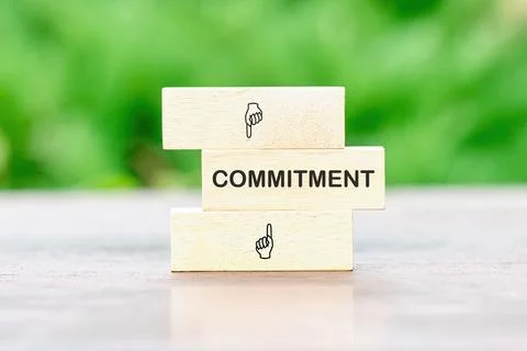 COMMITMENT Word Written on wooden bars on a green background of plants out .. Stock-Fotos