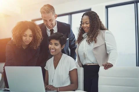 Committed to a collaborative work culture. a group of colleagues using a laptop 스톡 사진