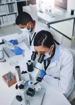 Committed to finding a cure. two young researchers working in a laboratory. Stock Photos