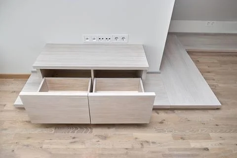 Commode for TV set of white oak lumber with open drawers on a wooden podium Stock Photos