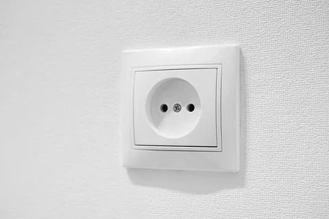Common cheap plastic AC power wall outlet. German circular recess socket with Stock Photos