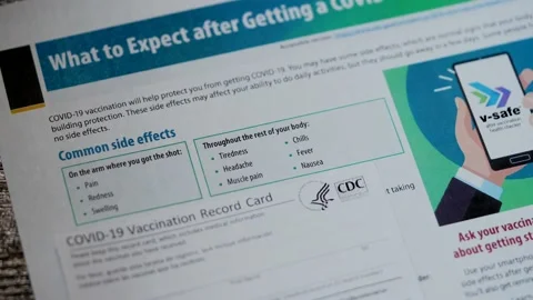 Common side effects list and COVID-19 Vaccination Record card, close up view Video stock 155410774