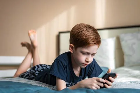 Communication and technology concept - ginger boy thinking with smartphone, t Foto stock