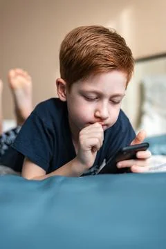 Communication and technology concept - ginger boy thinking with smartphone, p Stock Photos