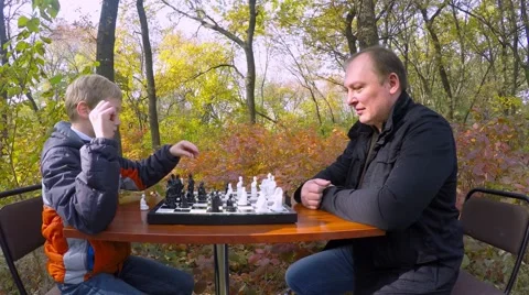 Communication between father and son during a game of chess in the park. Video stock 56310932
