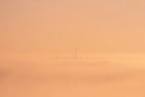 Communication masts on a hill surrounded by dense fog. Stock Photos