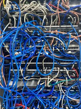 Communication rack with messy patch cables blue and grey closeup view Stock Photos