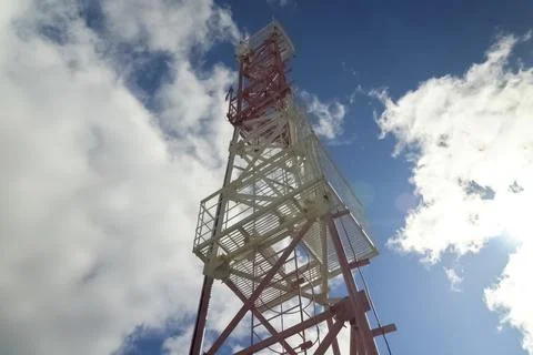 Communication tower against the background of a sky with clouds. Stock Photos