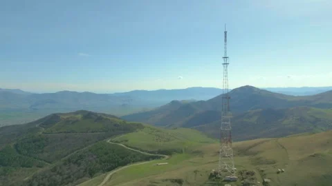 Communication tower on the background of high rocky mountains and blue sky. Stock Footage 254448992