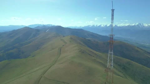 Communication tower on the background of high rocky mountains and blue sky. Stock Footage 254449444