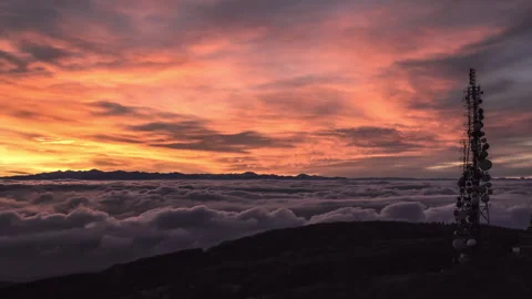 Communication tower silhouetted against a dramatic sunset sky over a sea Stock Footage 264558241