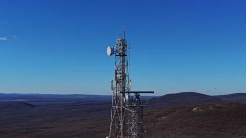 Communication tower stands tall among green hills on clear day Stock Footage 335144224