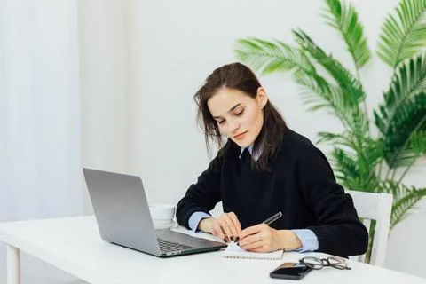 Communication woman at the computer makes a note in a notebook remote work 写真素材