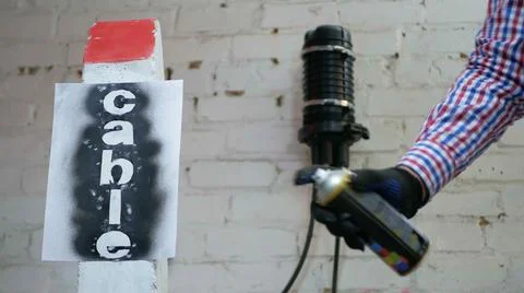 Communication worker draws on the warning cable post Stock Photos
