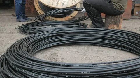 A communications engineer spins an optical cable from a large wooden cable drum. Stock Footage 127065163