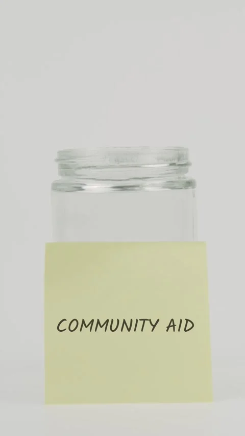 Community aid text or word on yellow sticky note attached to glass jar Stock Footage 311694857