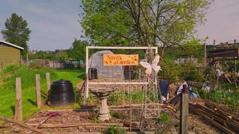 Community garden personalized plot with wooden sign and birdbath reversing low Vídeos de archivo 334643376