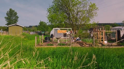 Community garden plot with wooden sign and rustic fencing reversing over tall Vídeos de archivo 334643380