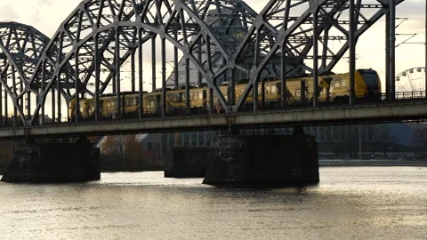 Commuter electric train moving across metallic railway bridge above Daugava R Stock Footage 320803976