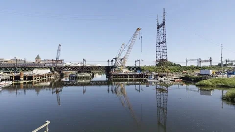 Commuter train crossing a river bridge under construction 스톡 동영상 342764154
