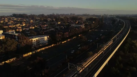 Commuter Train on Elevated Track Moving Fast Through Suburbs at Sunny Daybreak Stock Footage 157046568