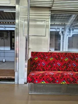 Commuter train interior with vibrant red patterned seat. Stock Photos