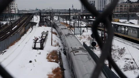 Commuter train moving away seen from above through chainlink fence Stock Footage 148454962