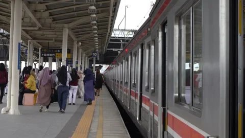 Commuter train passengers get off and board the train at a station Stock Footage 300543301