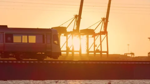 A commuter train passes a sunset with flare and light making a silhouette. Perth Stock Footage 125720569