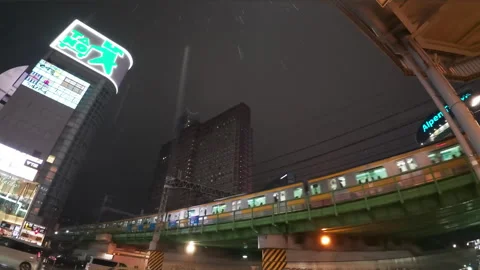 Commuter train passing over a bridge in a bustling urban area of Tokyo Stock Footage 329849117