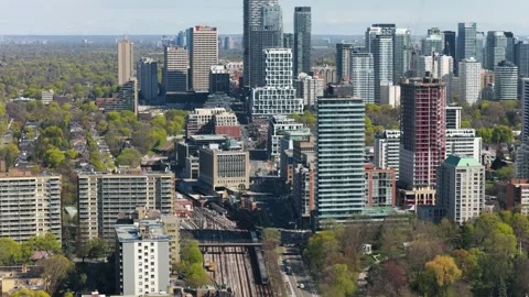 Commuter train passing through Toronto's vibrant cityscape, traveling between hi Stock Footage 334695893