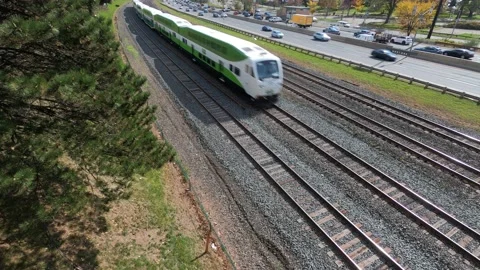 Commuter train on rail tracks parallel to highway. Video stock 143933634
