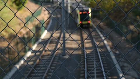 Commuter Train Rounds Curve Then Rack Focuses to Bridge Fence Vídeos de archivo 297875083
