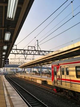 Commuter train stopped at a modern elevated railway station during golden hour Stock Photos