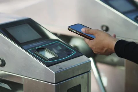 Commuter Using Mobile Phone for Contactless Payment at Transit Turnstile Gate in Stock Photos