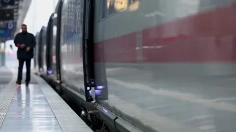 Commuter Waiting Beside Modern Train at Indoor Railway Station Platform Stock Footage 334053480