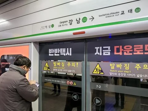 A commuter waiting at the platform in front of a subway train station doors Stock Photos