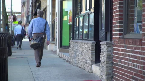 Commuter walking down a morning side walk heading to work Stock Footage 65385186