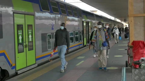 Commuters get off the train wearing protective masks. 库存影片 130949177