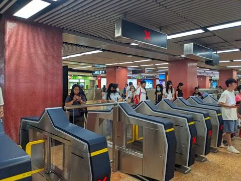 Commuters passing through modern electronic ticket gates at a busy Hong Kong MTR Stock Photos