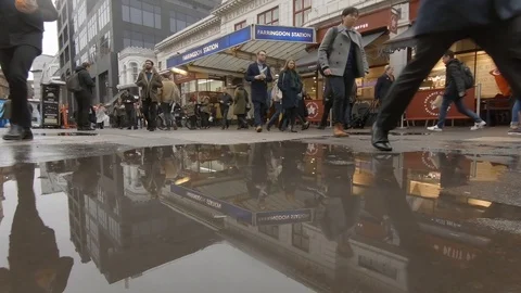 Commuters reflected in puddle by the old Farringdon Tube Station on a rainy day 스톡 동영상 99038604