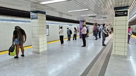 Commuters wait on a subway station platform. Stock Photos