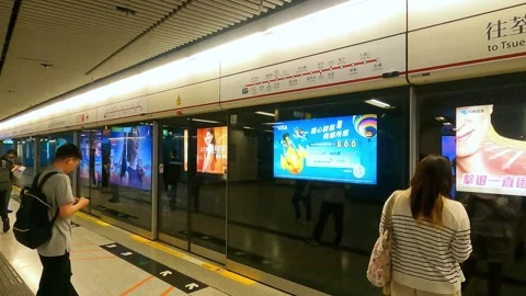 Commuters wait for the train to arrive at the station in Hong Kong. A woman is Stock Footage 341700578