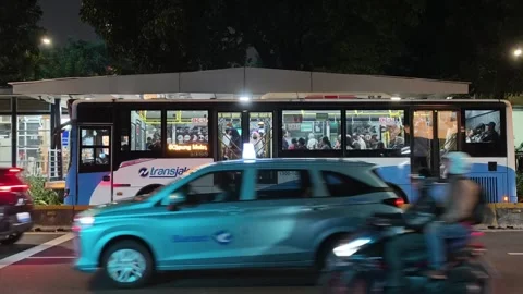 Commuters Waiting at Bus Shelter During Daily Urban Commute at Night Stock Footage 338988019