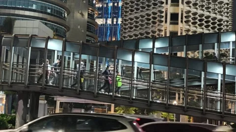 Commuters Walk Across an Elevated Pedestrian Bridge Stock Footage 338444667