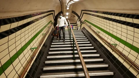 Commuters walking down stair case inside train station wearing face masks Stock Footage 141384643