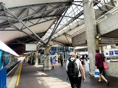 Commuters walking through busy train station platform under modern steel ro.. Stock Photos