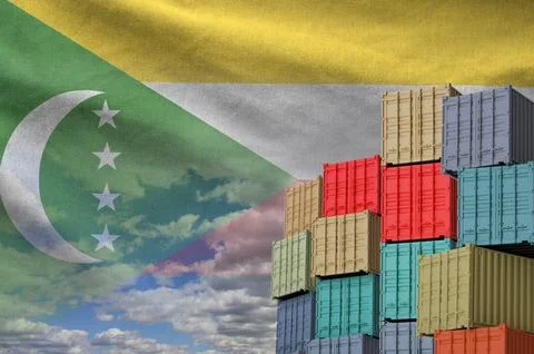 Comoros flag and big stack of shipping cargo containers in docks with sky Stock Photos