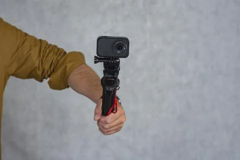 Compact action camera on a flexible tripod in hand on a light background. Stock Photos