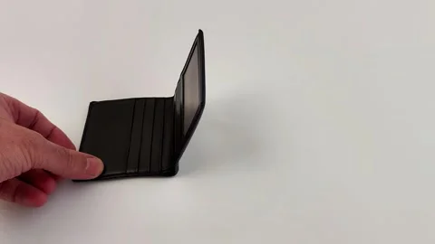 Compact Black Wallet Folded by Hand Against White Backdrop Video stock 321118297